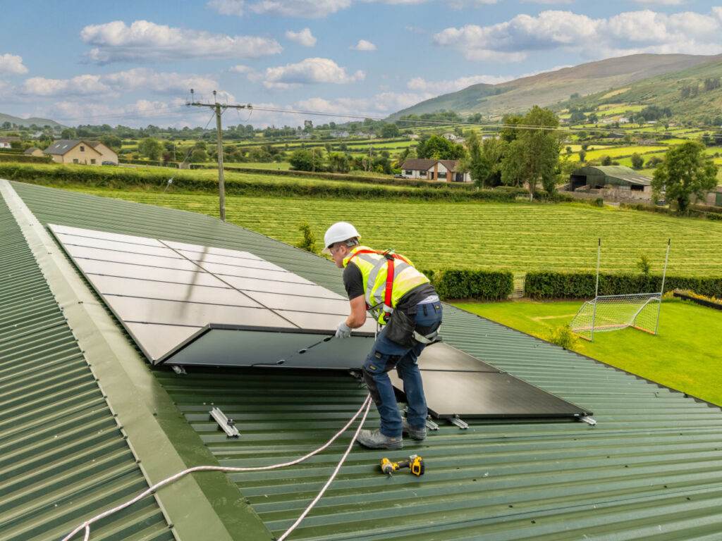 Installer fitting solar panels to a commercial roof